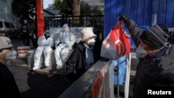 12일 중국 베이징에서 신종 코로바이러스 감염자 발생으로 출입통제되고 있는 아파트 단지 주민이 배달원으로부터 음식을 받고 있다.