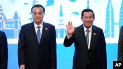 Cambodia Prime Minister Hun Sen waves as China's Premier Li Keqiang stand next to him during group photo of the ASEAN - China Summits