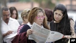 Voters read the a sample ballot as they wait in line to cast their vote in Hialeah, Florida, November 6, 2012.