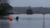 FILE - James Taylor and Joshua Myers paddle kayaks down a flooded residential street on their way to check on a friend's home, after heavy rains inundated the area with floodwaters in the McGraths Hill suburb of Sydney, Australia, July 6, 2022. 