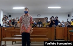 Terdakwa kasus pelanggaran HAM berat Paniai, Mayor Inf (Purn) Isak Sattu berdiri mendengarkan putusan hakim yang membebaskan dia dari semua tuntutan jaksa, Kamis (8/12) di Makassar. (foto screenshot)