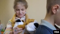 Stuffed dog with hugging paws comforts kids suffering from war's effects