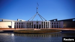 FILE - Tourists walk around the forecourt of Australia's Parliament House in Canberra, Australia, Oct. 16, 2017. 