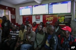 Customers watch screens in a sports betting shop in the low-income Kibera neighborhood of the capital Nairobi, Kenya, Monday, Dec. 5, 2022. (AP Photo/Brian Inganga)