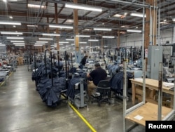 FILE - People work at Saitex's factory, which experiments with new robots to cut the cost of making blue jeans, in Los Angeles, California, U.S. September 21, 2022. (REUTERS/Timothy Aeppel)