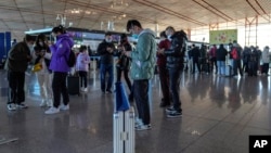 旅客在北京首都国际机场国际航班值机柜台办理登机手续后使用智能手机填写健康申明。（2022年12月29日，资料照片）