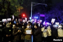 2022年11月28日，在中国北京，随着新冠肺炎疫情的持续，人们在为乌鲁木齐火灾遇难者守夜后，手持白纸抗议新冠肺炎疫情限制措施。