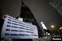 បាតុករ​ម្នាក់​កាន់​បដានៅ​ក្នុង​បាតុកម្ម​ប្រឆាំង​នឹងវិធានការ​រឹតត្បិតកូវីដ១៩​របស់​ចិន ដែល​ធ្វើ​ឡើង​នៅ​ទី​ក្រុង​ Cologne ប្រទេស​អាល្លឺម៉ង់ កាល​ពី​ថ្ងៃ​ទី​៣០ ខែ​វិច្ឆិកា ឆ្នាំ​២០២២ ​ខណៈ​អ្នក​ចូលរួម​រំឭក​ដល់​អ្នក​ស្លាប់​នៅ​ក្នុងអគ្គិភ័យ​មួយ​កន្លែង​នៅ​ទីក្រុង Urumqi ភាគ​ពាយ័ព្យ​ប្រទេស​ចិន។