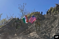 Seorang tentara India dan AS, masing-masing membawa bendera negaranya, berlari ke atas bukit selama pertemuan bersama Indo-AS. latihan militer di negara bagian Uttarakhand, India, 30 November 2022. (Foto: AP)