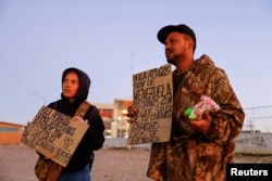 2023年1月7日，来自委内瑞拉的移民在美墨边境举着标牌寻求救助。