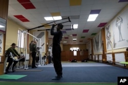 Ivan Moroz, who was injured while working in a gas production facility, exercises alongside Ukrainian soldiers in a physical therapy room at a rehabilitation center in Kharkiv region, Ukraine, Friday, Dec. 30, 2022. (AP Photo/Vasilisa Stepanenko)