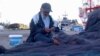 A fisherman mends his net in Zarzis, Tunisia. (Lisa Bryant/VOA)