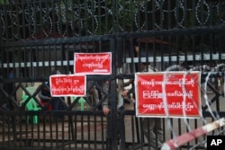 FILE - Police officers and prison personnel are seen behind the entrance gate of Insein prison in Yangon, Myanmar, Oct. 18, 2021.
