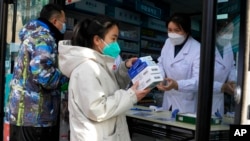 FILE - A resident carries away medicine bought at a pharmacy in Beijing, Dec. 9, 2022.