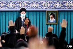 Pemimpin Tertinggi Iran Ayatollah Ali Khamenei berdiri di sebelah potret mendiang pendiri republik Islam Ayatollah Ruhollah Khomieni selama pertemuan di ibu kota Teheran, 4 Januari 2023. (KHAMENEI.IR / AFP)