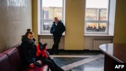 A woman holds her dog as she waits for an evacuation train at Kherson rail station in Kherson on Dec. 30, 2022, amid the Russian invasion of Ukraine.