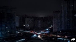Cars drive past residential blocks which were de-energized after a Russian rocket attack in Kyiv, Ukraine, Nov. 23, 2022.