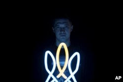 Mykhailo Fedorov, menteri transformasi digital Ukraina, berpose di belakang lampu berbentuk trisula Ukraina, simbol nasional, di kantornya di Kyiv, Ukraina, Rabu, 21 Desember 2022. (AP/Felipe Dana)