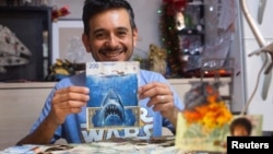 Artist Sergio Diaz holds intervened Argentine pesos bills and a US dollar depicting Steven Spielberg's movie "Shark" as a parody of Argentina's ever-increasing inflation, in Salta, Argentina, December 30, 2022. (REUTERS/Javier Corbalan)