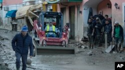 Workers clear mud and debris from a street after heavy rainfall triggered deadly landslides, in Casamicciola, on the southern Italian island of Ischia, Nov. 27, 2022.