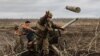 A Ukrainian serviceman of an artillery unit throws an empty shell as they fire towards Russian positions on the outskirts of Bakhmut, eastern Ukraine, Dec. 30, 2022. 