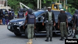 FILE - Police officers stop a vehicle at a checkpoint in Abuja, Nigeria, Oct. 21, 2021. A women and her unborn child were shot and killed Sunday after an officer opened fire at her family’s vehicle at a checkpoint in Ajah. The circumstances remain unclear.