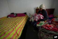 Single mother Tania Herrera holds her 20-day-old daughter Sara Milena as she breastfeeds her in the one-room shack where they live with her parents in Quito, Ecuador, Nov. 15, 2022.
