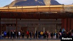 FILE - After crossing the Rio Bravo River, migrants queue near U.S.-Mexico border fence to request asylum in El Paso, Texas, Jan. 5, 2023. 