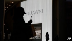 Siluet pembeli di luar toko ritel Huawei di Beijing, Jumat, 30 Desember 2022. (AP/Ng Han Guan)