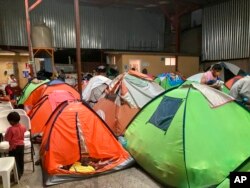 FILE - Migrants are seen shortly before lights-out at Juventud 2000 shelter in Tijuana, Oct. 13, 2022.