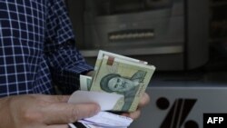 FILE - Seorang pria menarik uang kertas Rial Iran dari ATM di ibu kota Teheran, 31 Juli 2018.