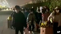 រូប​ឯកសារ៖ រូបថត​ពី​វីដេអូ​ដែល​ផ្សាយ​ដោយ Hangpai Xingyang នេះ​បង្ហាញ​មនុស្ស​ដែល​មាន​វ៉ាលីស​​ចាកចេញ​ពី​រោងចក្រ​ក្រុមហ៊ុន Foxconn នៅ​ក្រុង Zhengzhou ខេត្ត Henan ប្រទេស​ចិន​កាល​ពី​ថ្ងៃ​ទី​២៩ ខែ​តុលា ឆ្នាំ​២០២២។