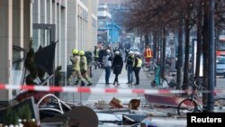 Emergency services work on a street outside a hotel after a burst and leak of the AquaDom aquarium in central Berlin near Alexanderplatz, with water poured out onto the street, in Berlin, Germany, Dec. 16, 2022. 