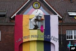 Aksi protes seorang aktivis iklim, dengan bergelantungan dengan tali di desa Luetzerath dekat Erkelenz, Jerman, Rabu, 11 Januari 2023. Polisi berupaya mengusir para aktivis yang berdemo untuk mencegah pembongkaran desa tersebut yang akan digunakan untuk perluasan tambang batubara. (AP/Michael Probst)