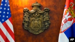 A Serbian coat-of-arms is seen between US, left, and Serbian flags during the meeting of US State Department Counselor Derek Chollet and Serbian Prime Minister Ana Brnabic in Belgrade, Serbia, Jan. 12, 2023. 