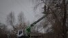 Workers of the electricity supply company DTEK maintain power lines by cutting off excess branches in Kyiv, Ukraine, Dec. 8, 2022.