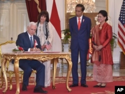 U.S. Vice President Mike Pence (left) with his wife, Karen, (second from left) signs the guest book as Indonesian President Joko Widodo and his wife, Iriana, look on, during their meeting at Merdeka Palace in Jakarta, Indonesia, April 20, 2017.