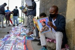 FILE - Ethiopians read newspapers and magazines reporting on the military confrontation in the country, one of which shows a photograph of Prime Minister Abiy Ahmed, on a street in the capital, Addis Ababa, Nov. 7, 2020.