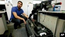 FILE - Software engineer Nicholas Otero speaks with a colleague, not pictured, about features on a Centaur robot, right, at Endeavor Robotics in Chelmsford, Massachusetts, Aug. 28, 2018.