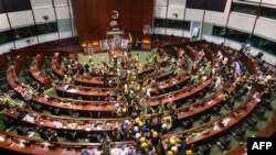 Sejumlah demonstran bergerak keluar dari ruang utama geduing pemerintahan Hong Kong dalam aksi protes pada 2 Juli 2019. (Foto: AFP/Anthony Wallace)