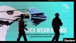 Neophodni radnici prolaze pored natpisa "Heroji nose maske" tokom karantina, Melburn, Australija, 28. maj, 2021.