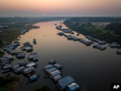 Surrounded by houses the lake in Carauari city is seen during sunrise, Amazonia, Brazil, Thursday, Sept. 1, 2022. Along the Jurua River, a tributary of the Amazon, riverine settlers and Indigenous villages are working together to promote the sustainable fishing of near magic fish called pirarucu. (AP Photo/Jorge Saenz)