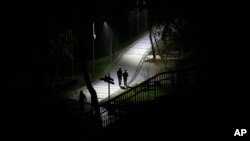 People walk in a park during a blackout in Kyiv, Ukraine, Sunday, Nov. 6, 2022. (AP Photo/Andrew Kravchenko)