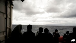 Migrants stand on the deck of the Ocean Viking rescue ship, in the Strait of Sicily, in the Mediterranean Sea, Nov. 5, 2022.