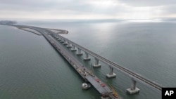 In this handout photo released by the Russian Federal Road Transport Agency (Rosavtodor) on Nov. 8, 2022, workers repair the side of damaged spans of the road section of the Crimean Bridge connecting Russian mainland and Crimean Peninsula.