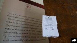 FILE - An Israeli army closure order hangs on a door of the Al-Haq human rights organization that was raided by Israel forces, in the West Bank city of Ramallah, Aug. 18, 2022. Israel raided offices of several Palestinian advocacy groups it had designated terrorist organizations.