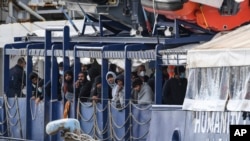 FILE - Migrants stand on the deck of the 'Humanity 1' rescue ship run by the German organization SOS Humanitarian, at harbor in the port of Catania, Sicily, southern Italy, Nov. 6, 2022.