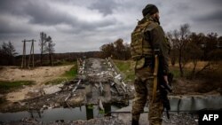 A Ukrainian serviceman stands at a destroyed bridge near the Ukrainian border with Russia near the village of Starytsya, Kharkiv region, on Nov. 5, 2022.