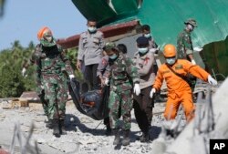 Rescuers carry the body of an earthquake victim recovered from debris of a collapsed mosque in Lombok, Indonesia, Aug. 7, 2018.
