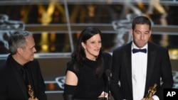 Dirk Wilutzky, from left, Laura Poitras and Glenn Greenwald accept the award for best documentary feature for “Citizenfour” at the Oscars on Sunday, Feb. 22, 2015, at the Dolby Theatre in Los Angeles. (Photo by John Shearer/Invision/AP)